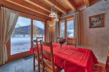 A dining room table with a red table cloth and a framed poster that says chamonix