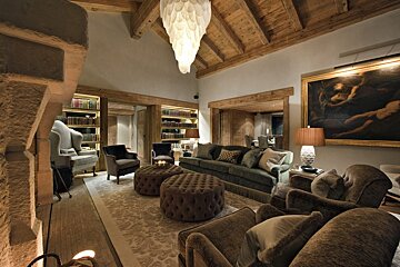 A living room with a couch chairs and ottomans