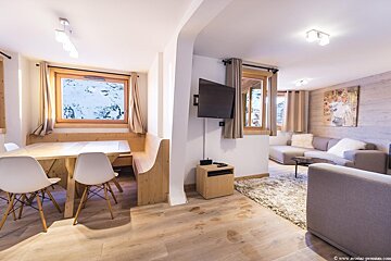A living room with a table and chairs and a flat screen tv