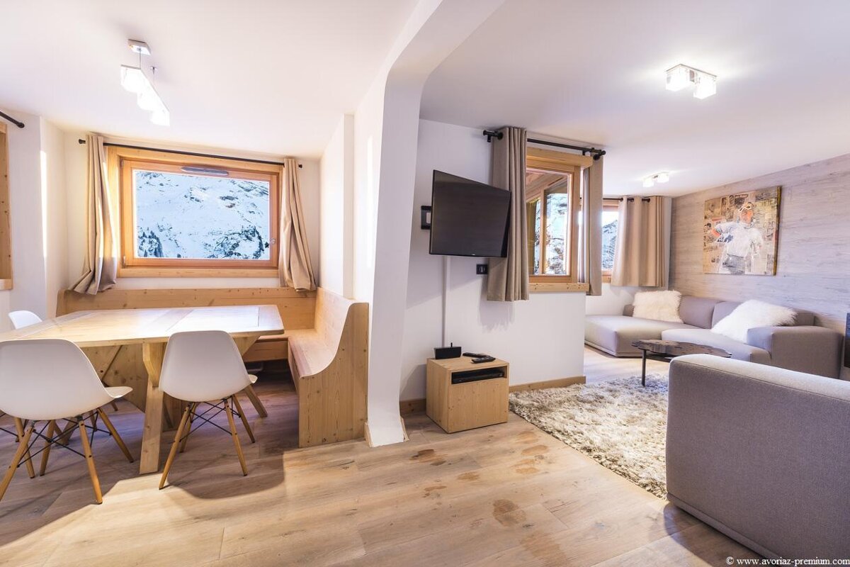 A living room with a table and chairs and a flat screen tv