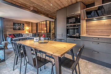A kitchen with a wooden table and black chairs