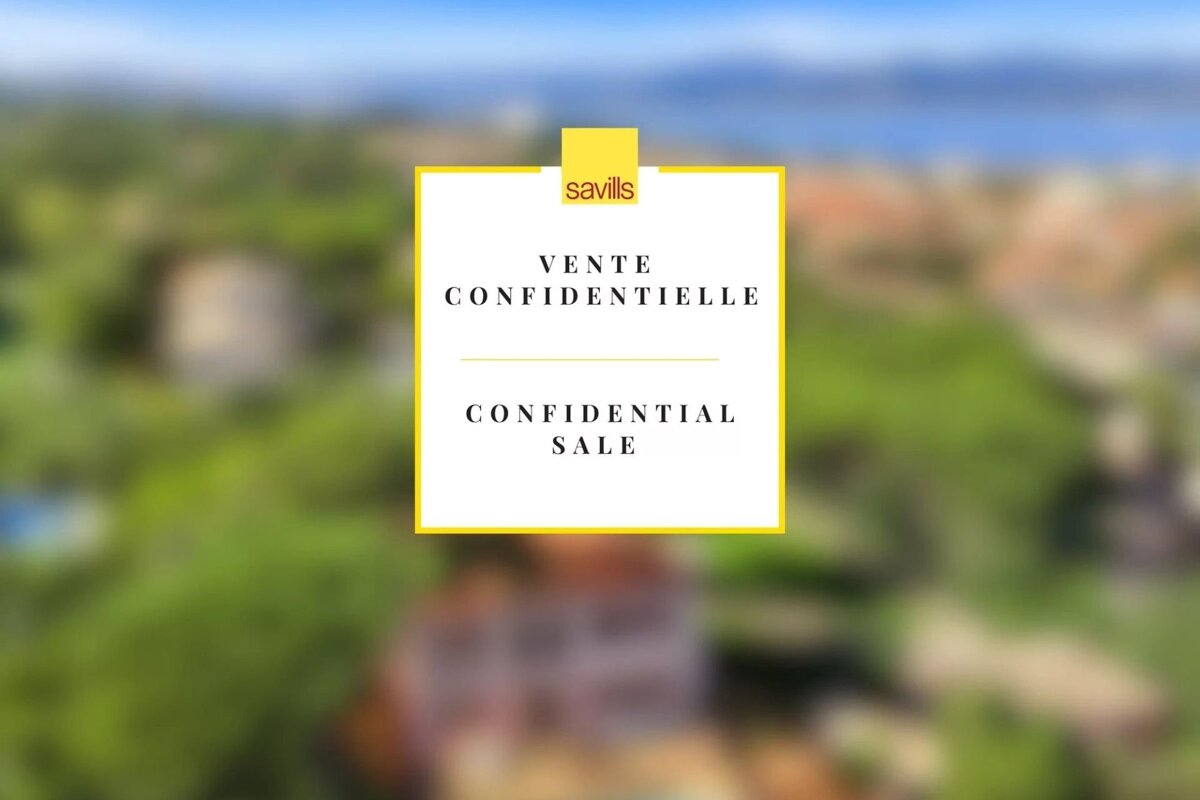 Blurred aerial view of a green, hilly landscape with houses and water. A white box with yellow border announces 