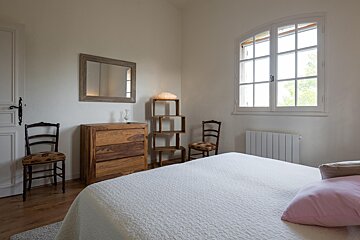 A bedroom with a bed a dresser and two chairs