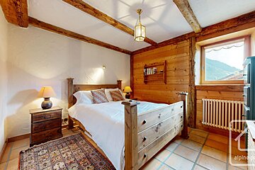 A bedroom with a wooden bed and a window with the word alpine on the bottom