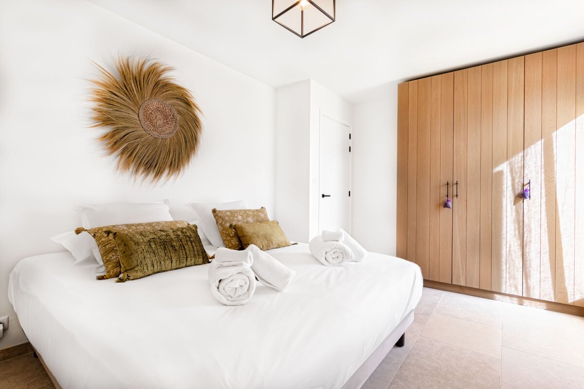 A bedroom with a white bed and a wooden wardrobe
