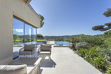 A patio with chairs and a swimming pool in the background