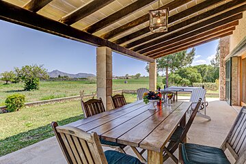 A wooden table and chairs on a patio with mountains in the background
