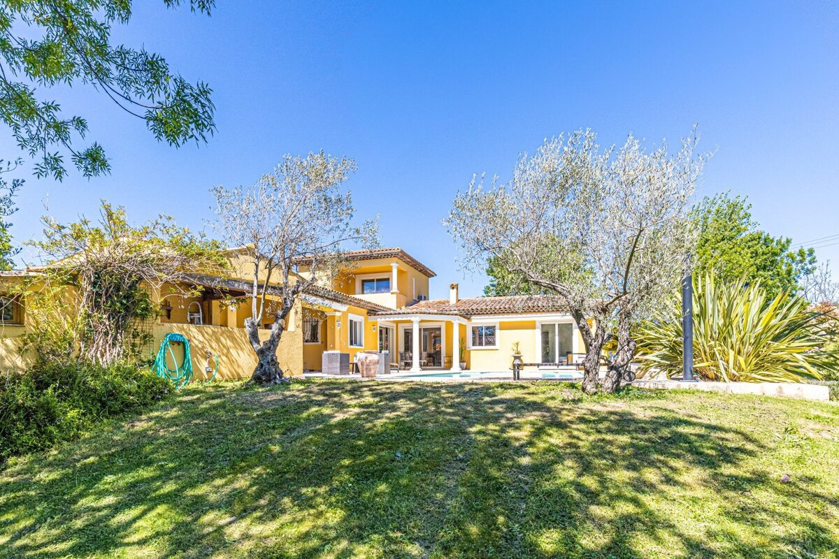 A large yellow house sits in the middle of a lush green field