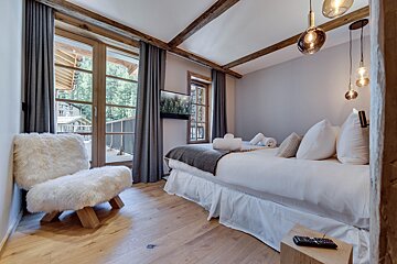 A bedroom with a bed a chair and a television