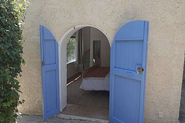 A blue door open to a bedroom with a bed