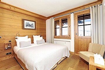 A bedroom with a bed a chair and a picture on the wall