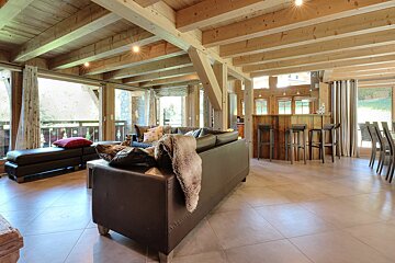 A living room with a couch and chairs and a wooden ceiling