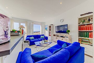 A living room with two blue couches and a flat screen tv