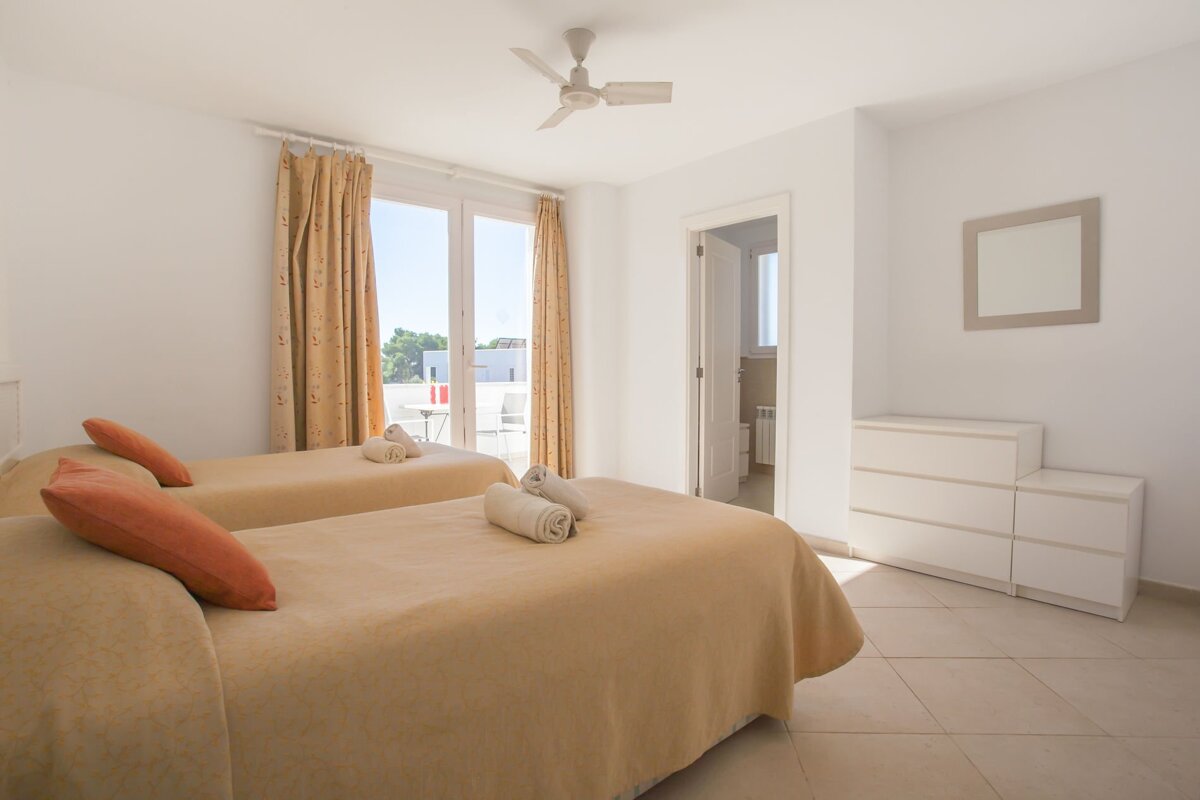 A bedroom with two beds and a ceiling fan