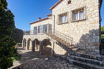 A stone building with stairs leading up to the second floor