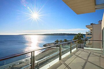 Bright balcony overlooking a sun-drenched blue ocean with a distant coastline under a clear sky.