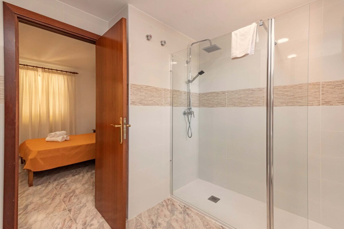 A bathroom with a walk in shower and a single bed
