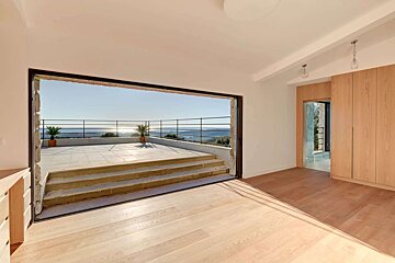 An empty room with a sliding glass door leading to a balcony overlooking the ocean