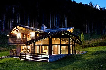 A house with a lot of windows is lit up at night