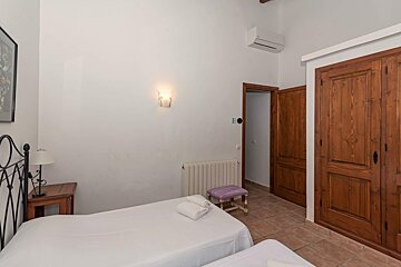 A bedroom with two beds and a purple stool