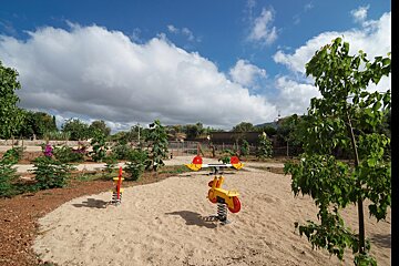 A playground with a red and yellow seesaw in the sand