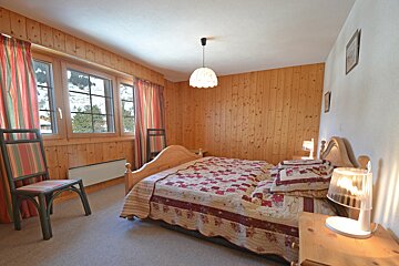 A bedroom with a bed a chair and two lamps
