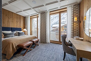 A hotel room with a large bed and a desk