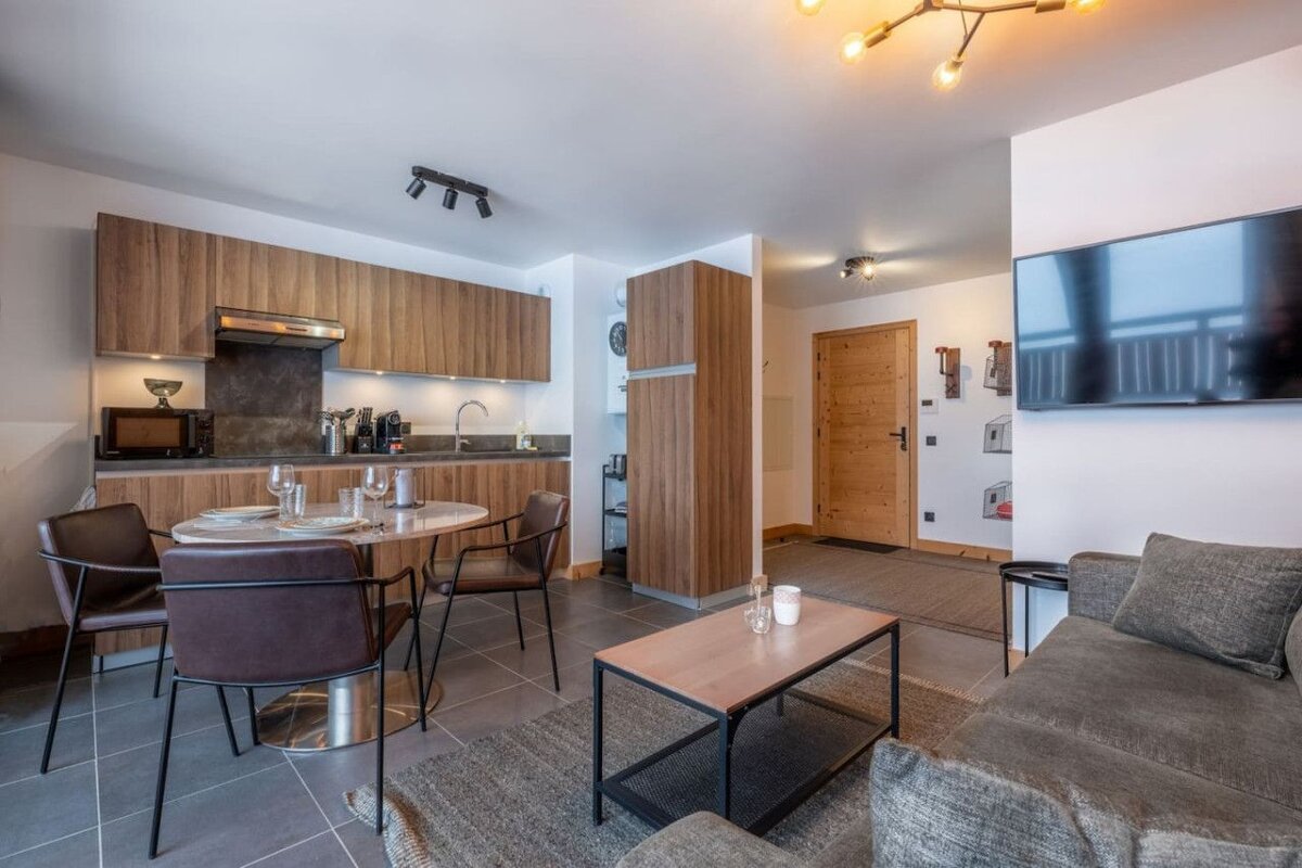 A living room with a table and chairs and a flat screen tv