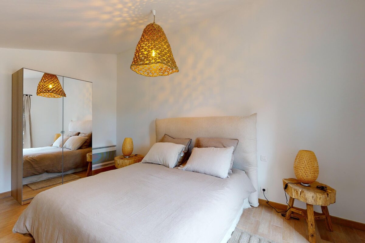 A bedroom with a bed and two lamps hanging from the ceiling