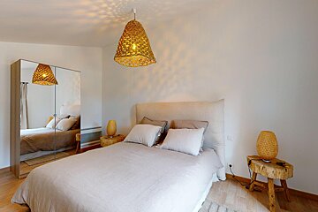 A bedroom with a bed and two lamps hanging from the ceiling