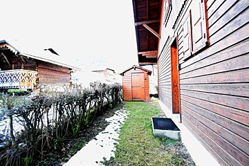 Wooden alpine chalets and a small shed with patches of melting snow on the ground.
