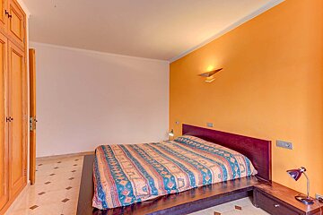 A bedroom with a bed and orange walls