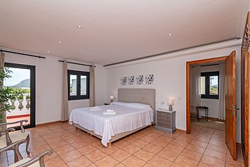 A bedroom with a large bed and a balcony