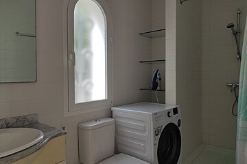 A bathroom with a washing machine and a toilet