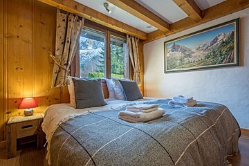 A bedroom with two beds and a painting on the wall