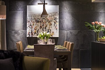 A dining room with a painting on the wall above the table