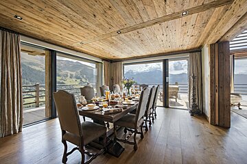 A large dining room with a wooden table and chairs