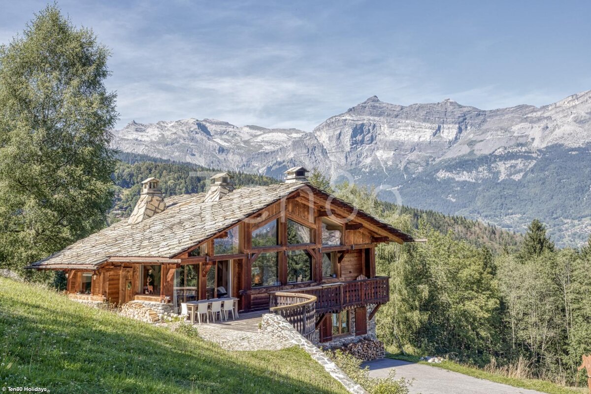 A large wooden house with mountains in the background