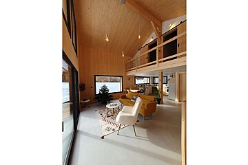 A living room with a yellow couch and a white chair