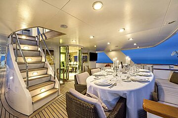 A dining area on a boat with a table and chairs