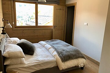 A bedroom with a large bed and a window