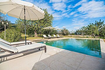 A swimming pool surrounded by chairs and umbrellas on a sunny day