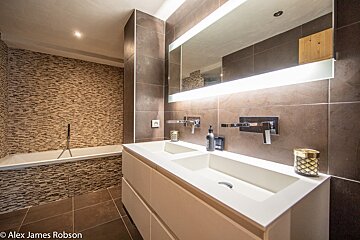 A bathroom with two sinks and a mirror by alex james robson