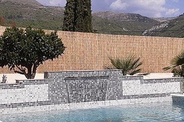 A swimming pool with a waterfall and mountains in the background