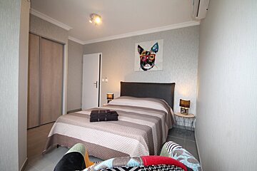 A bedroom with a dog painting on the wall above the bed