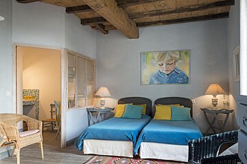 A bedroom with two beds and a painting on the wall