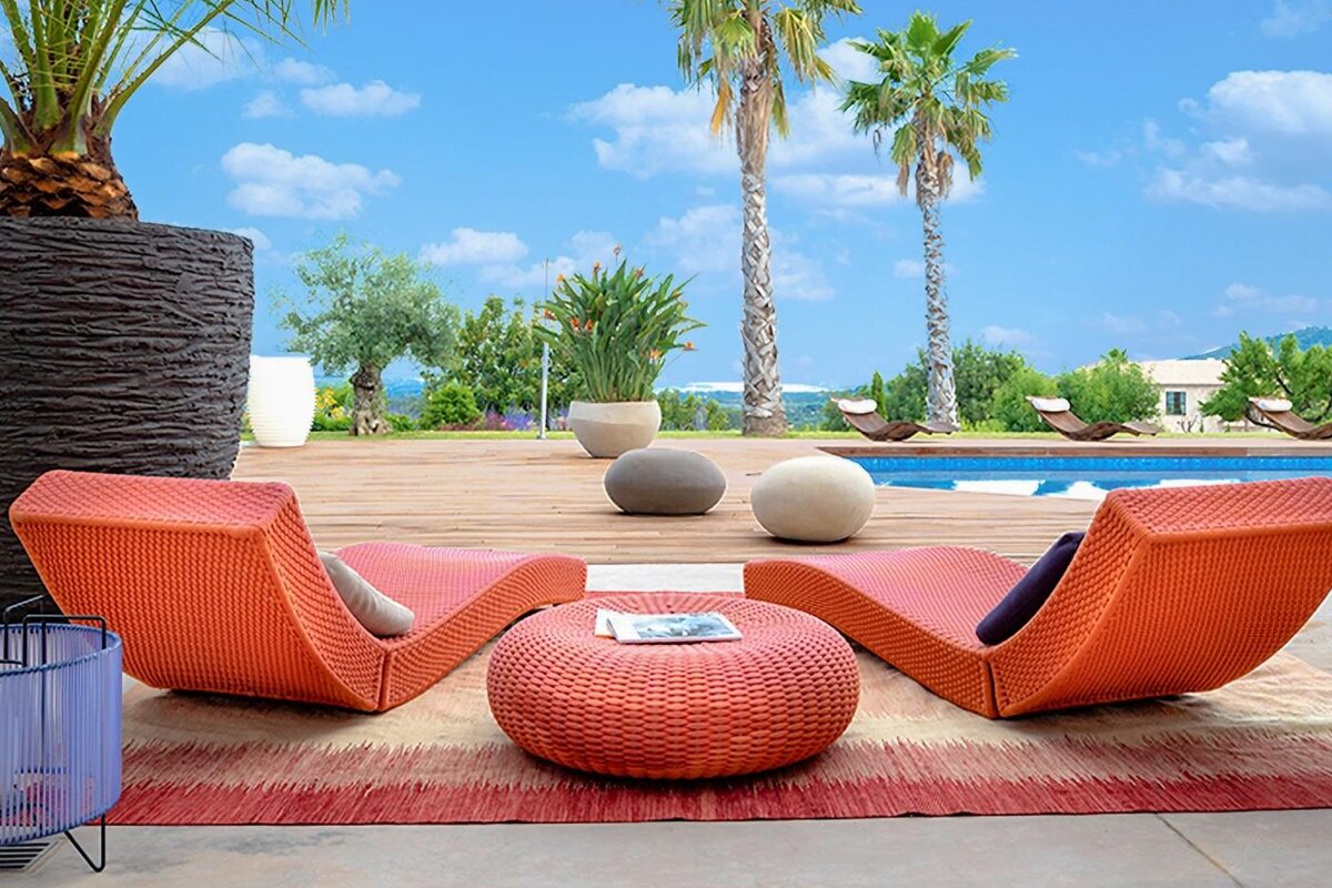 Two orange lounge chairs sit on a wooden deck near a swimming pool