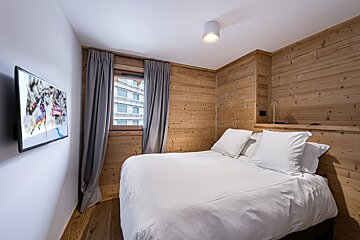 A bedroom with a bed and a flat screen tv