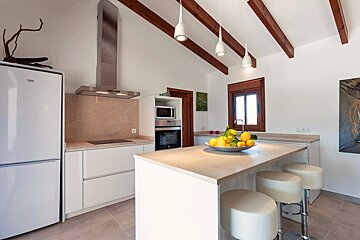 A kitchen with a beko refrigerator and stools