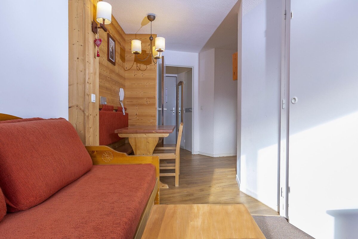 A living room with a red couch and a wooden table